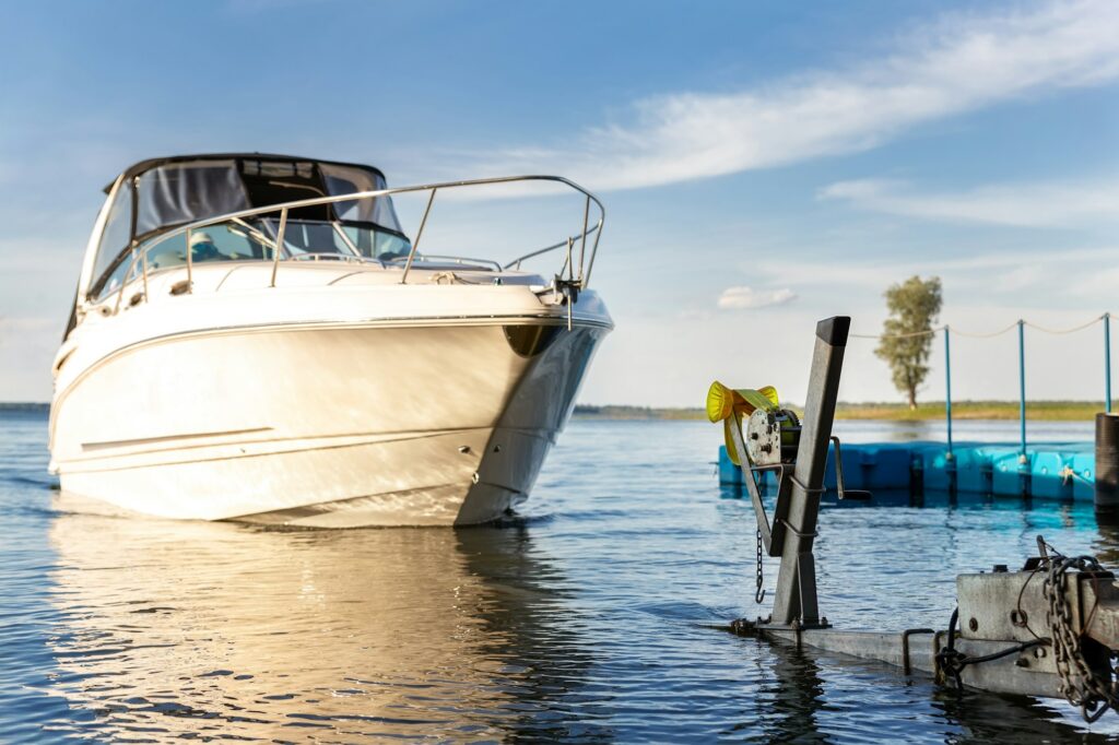 Big luxury cabin motorboat cruiser yacht launching at trailer ramp on river or lake.